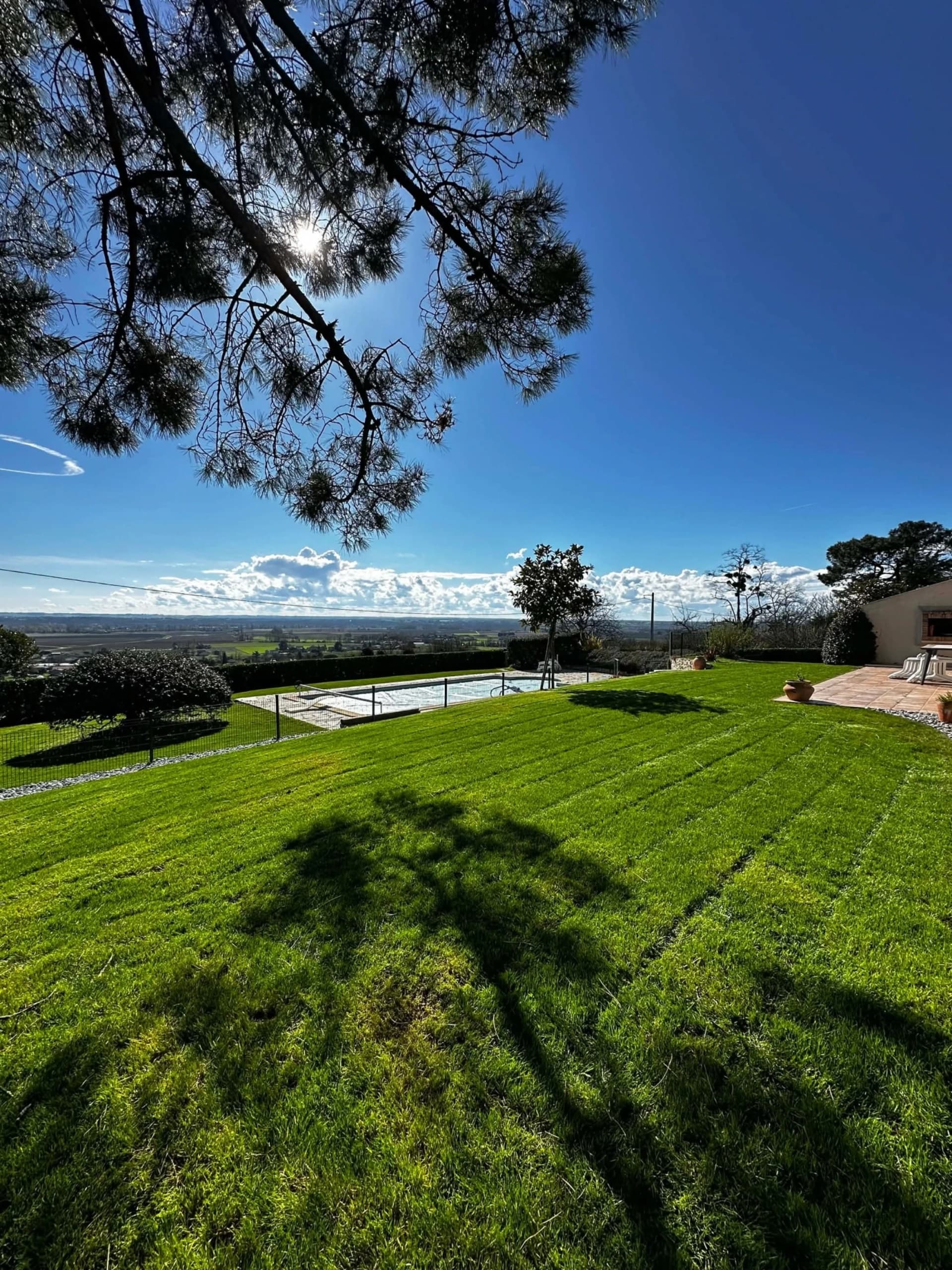 Grande pelouse tondue avec vue dégagée sur la campagne et piscine